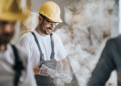 Ouvrier souriant avec un casque dans un chantier.