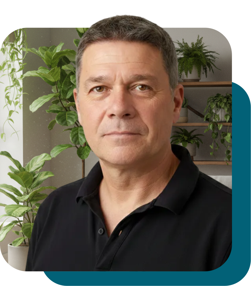 Adult man standing near green plants indoors.