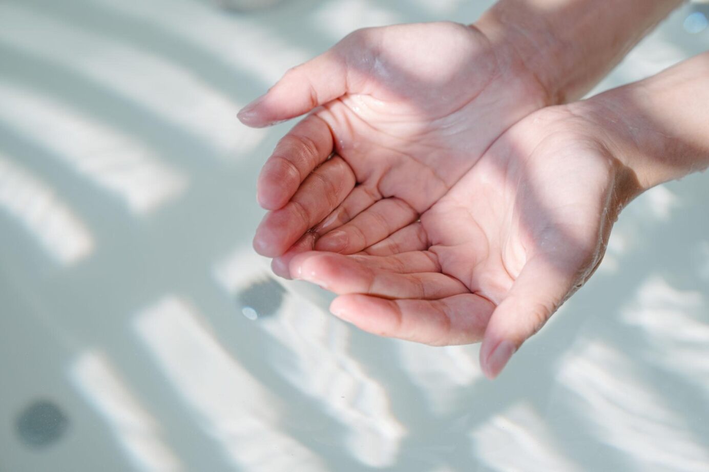 Open hands cupped over water surface.
